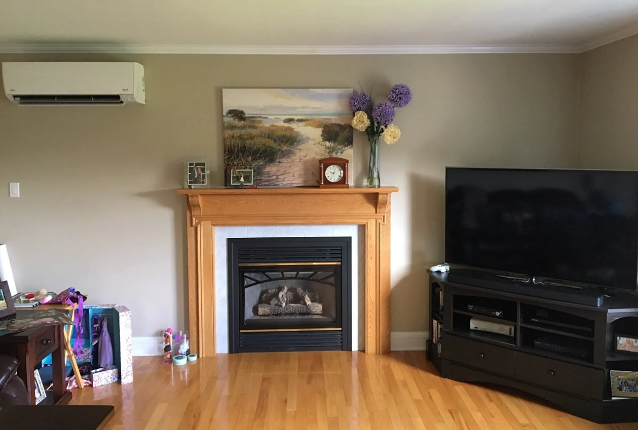 Living room with fireplace, TV, wood floors, beige walls, and floral decor.