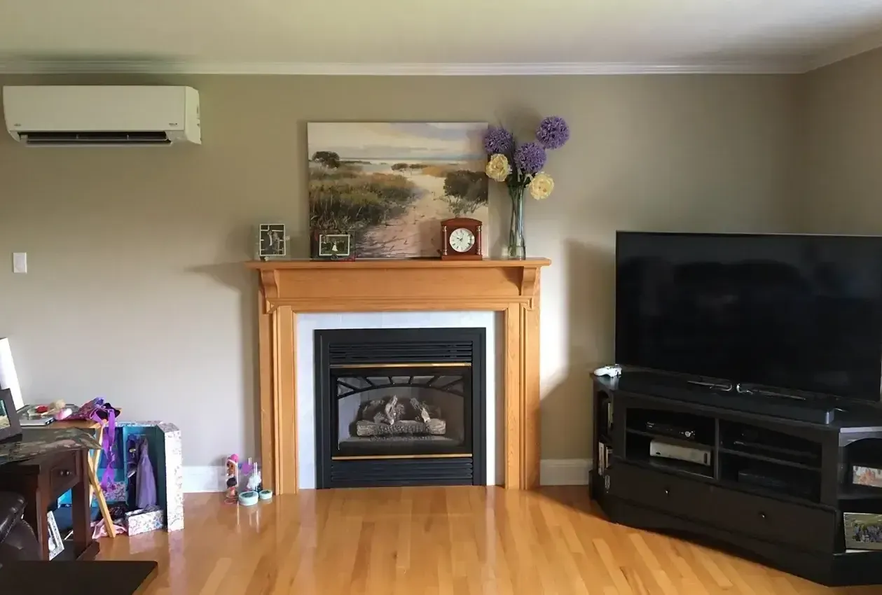 Living room with fireplace, TV, wood floors, beige walls, and floral decor.
