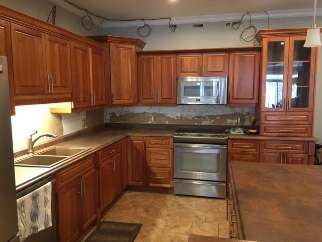 Kitchen with brown cabinets, stainless steel appliances, and a dark countertop, undergoing renovation.