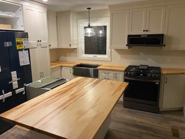 White kitchen with wood countertops, black appliances, and a large island.