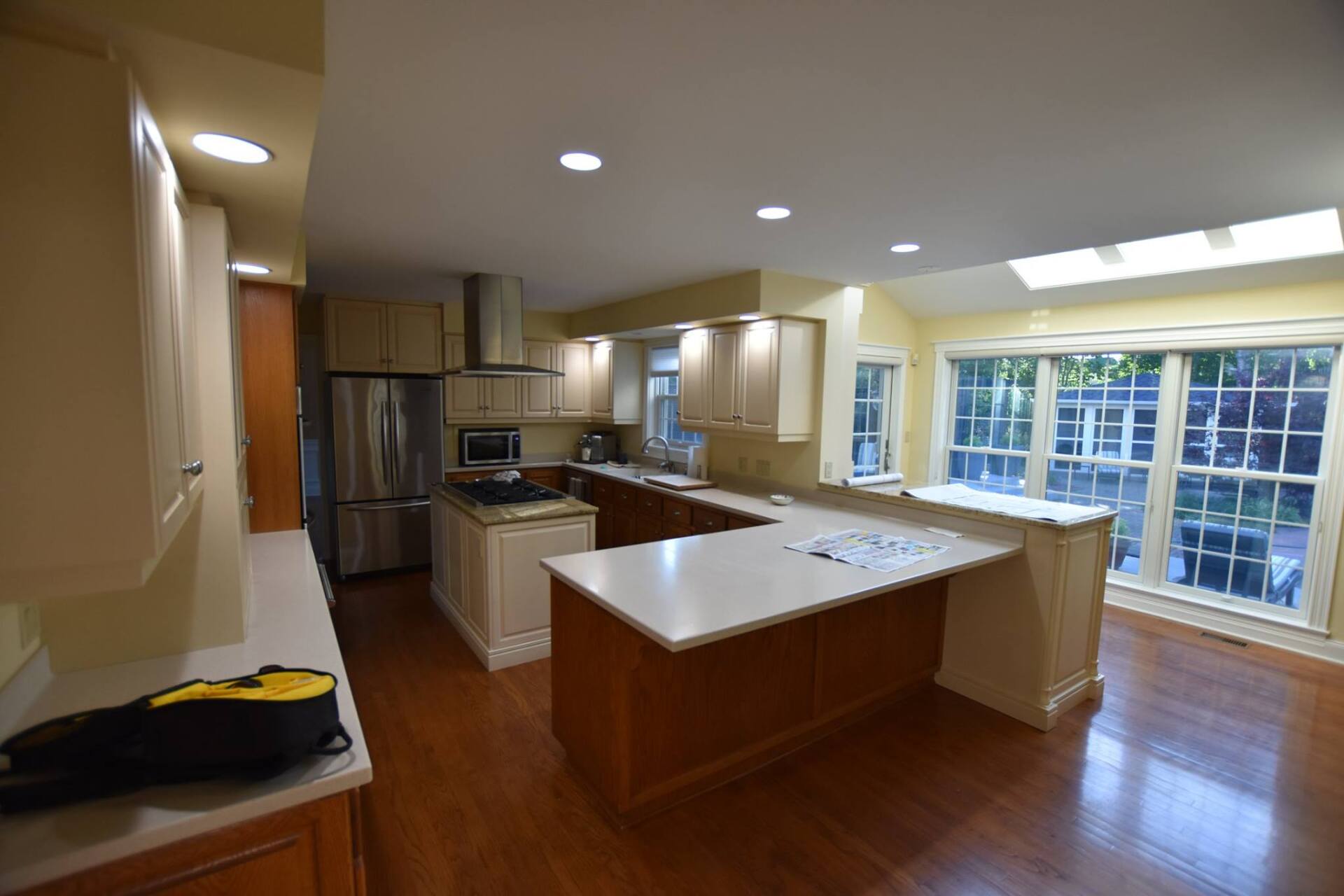 A modern kitchen with stainless steel appliances, light cabinets, and a central island with a white countertop.
