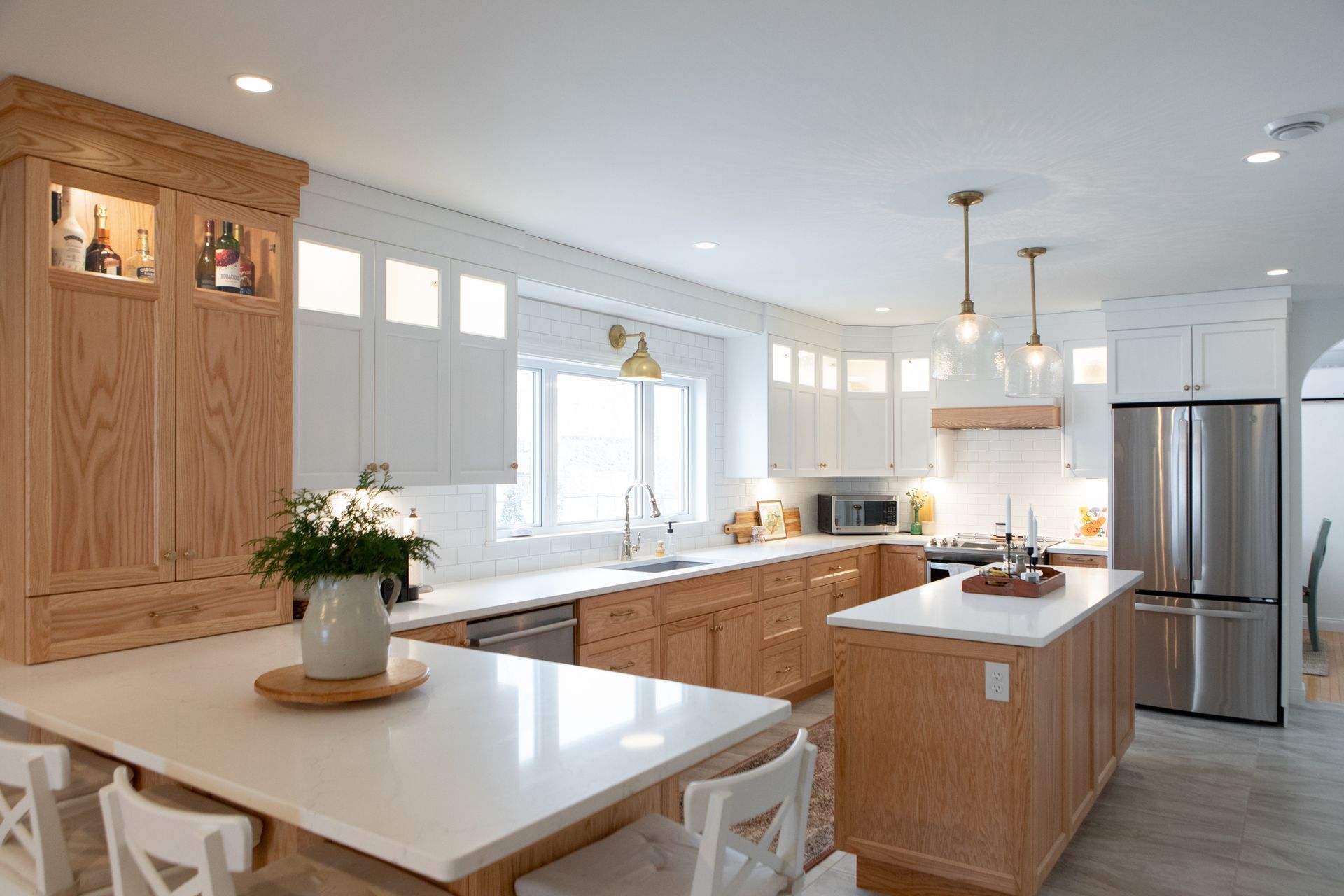 Spacious kitchen with light wood cabinets, white countertops, stainless steel appliances, and two islands.