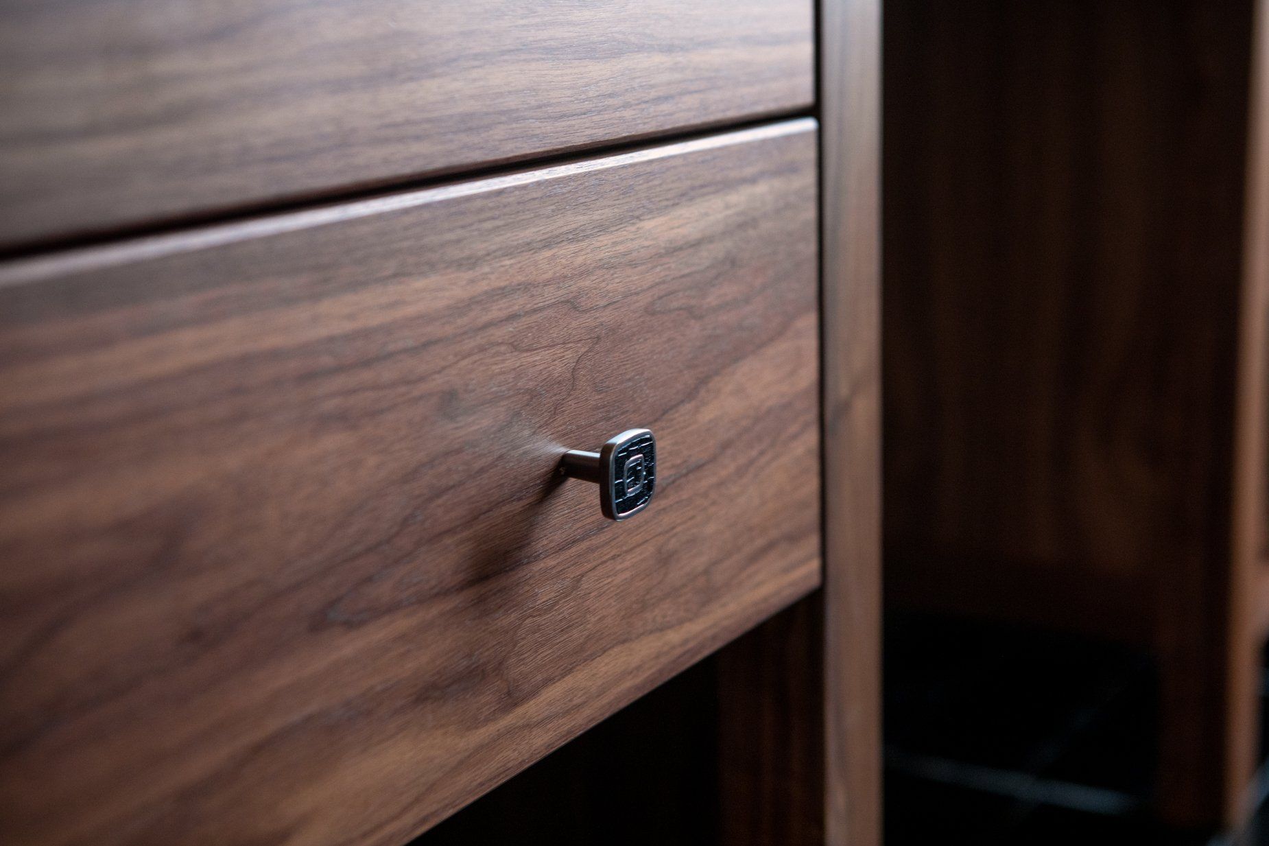 Close-up of a wooden drawer with a small, square metal knob.