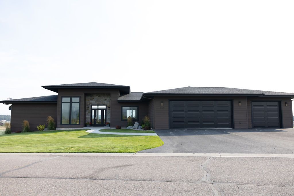 A large house with two garages is sitting on the side of the road.