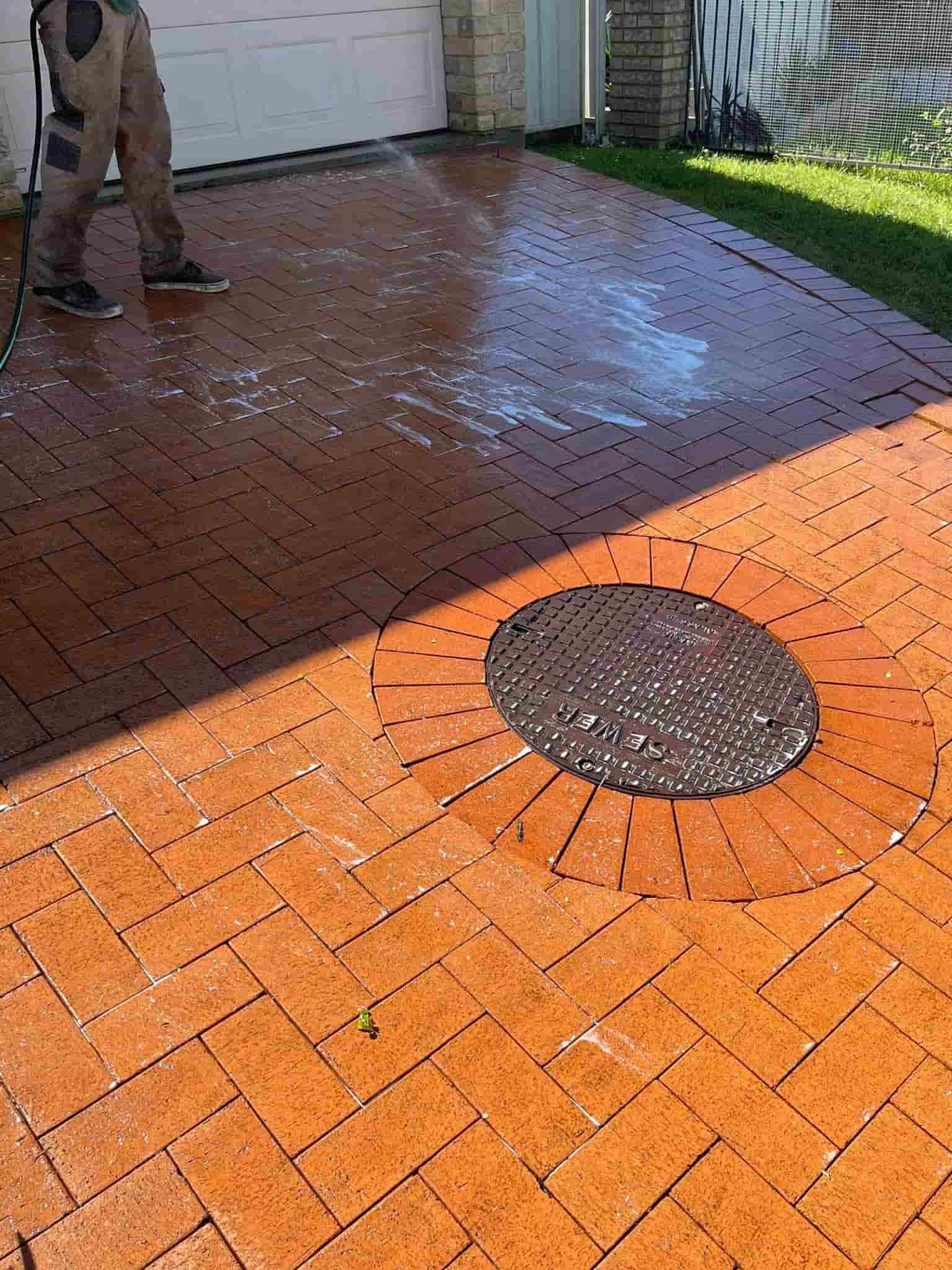 A Person Pressure Washes a Herringbone-patterned Brick Driveway — South Coast Pressure Washer in Shellharbour, NSW
