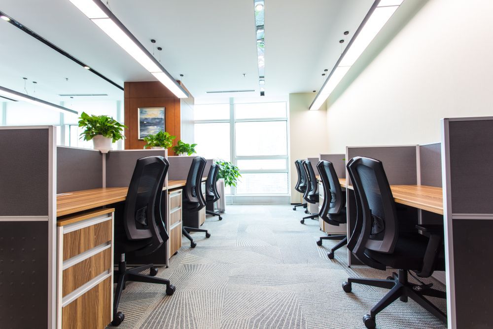 A row of cubicles in an office with chairs and desks.