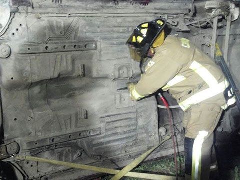 A fireman wearing a helmet is working on a car