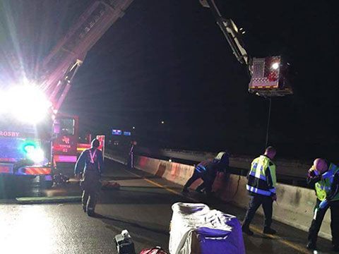 A group of firefighters are working on a highway at night.