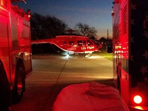 A red life flight helicopter is parked next to an ambulance