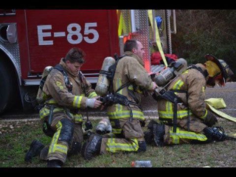 A group of fire fighters are replacing their air bottles on a scene.