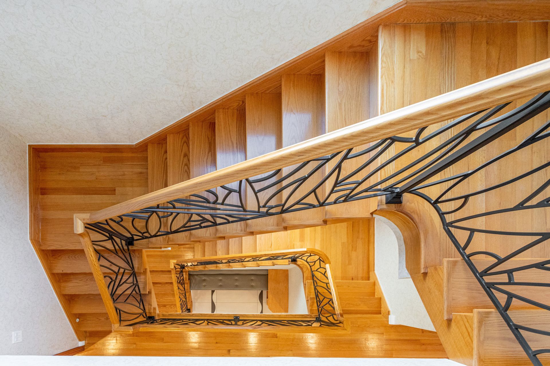 Wooden staircase with black metal railing, viewed from above.