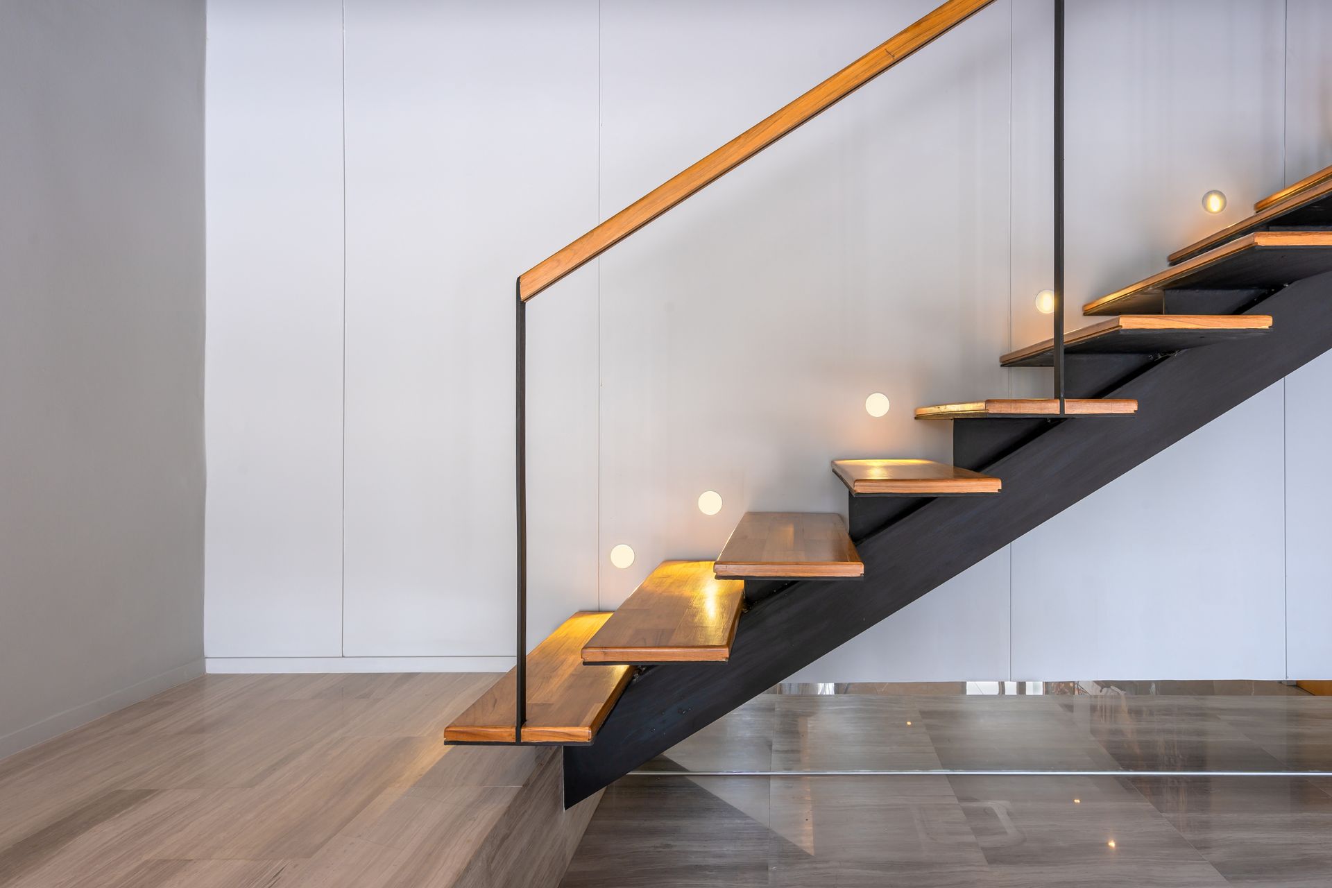 Wooden floating staircase with built-in lights, black metal frame, and glass panels.
