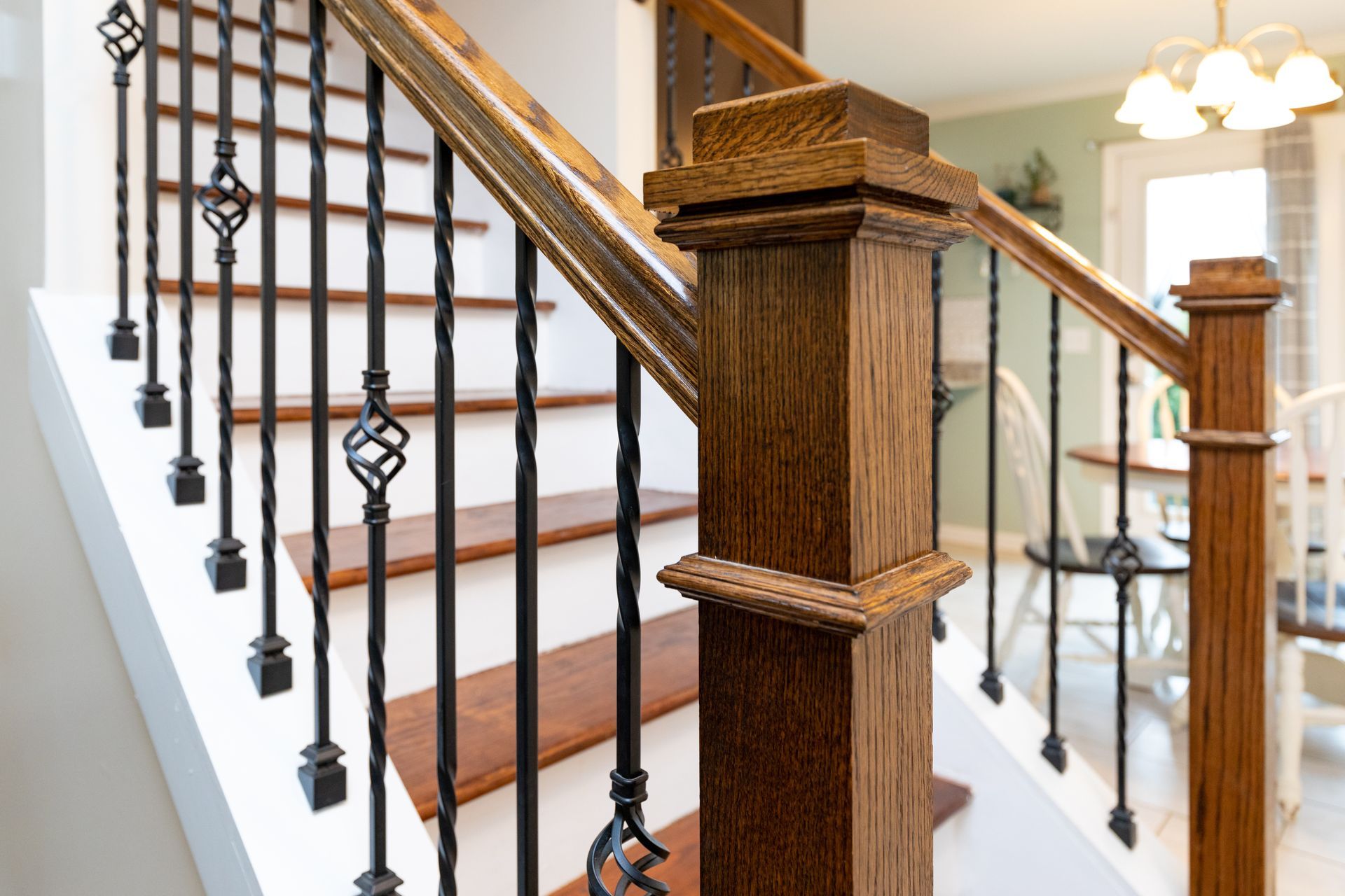 Wooden staircase with brown treads and handrails, black iron balusters, and white risers.