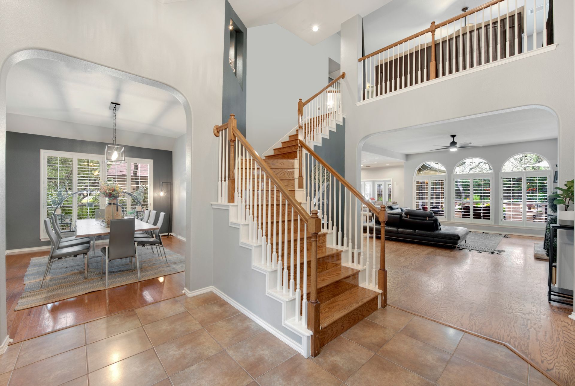 A spacious entryway with staircase, dining room, and living room. Neutral colors and natural light.