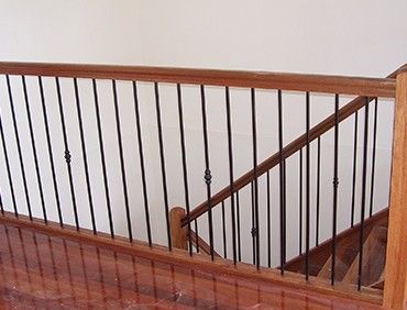 Wooden staircase with black metal balusters and wooden handrail.