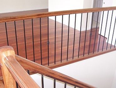 Wooden staircase with dark metal spindles and wood railing.
