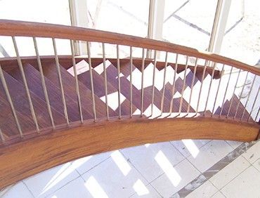 Wooden curved staircase with metal railings.