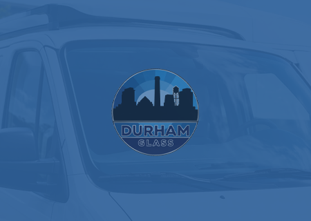 Durham Glass logo on a blue-tinted vehicle window with city skyline icon