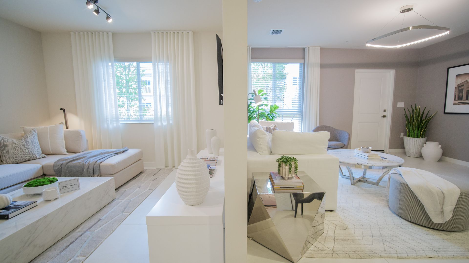 Bright modern living room with white sofa, cream rug, round mirror, and soft natural light at Atlantica at Dania Beach apartments in Dania Beach, FL.