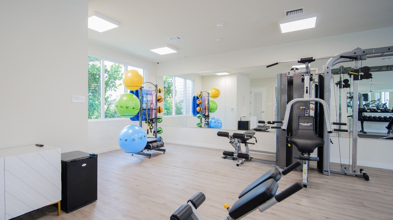 Bright modern gym with exercise machines, benches, and colorful balloons in a clean open space at Atlantica at Dania Beach apartments in Dania Beach, FL.