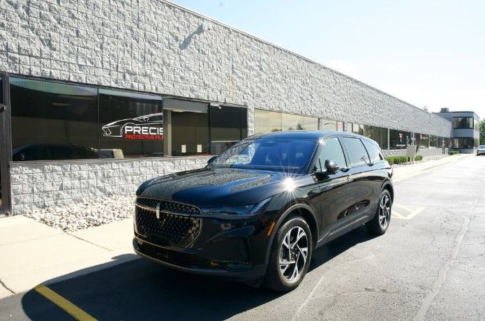 Black SUV parked beside a storefront on a sunny street.