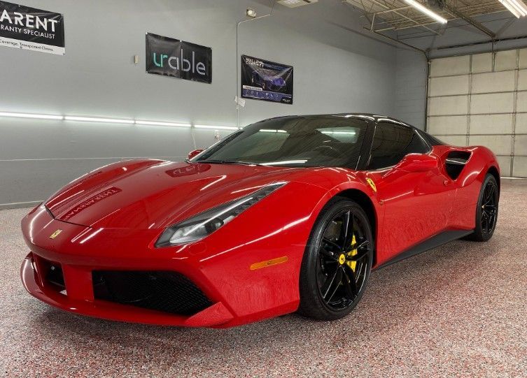 Red sports car in a showroom with a glossy floor and garage door in the background