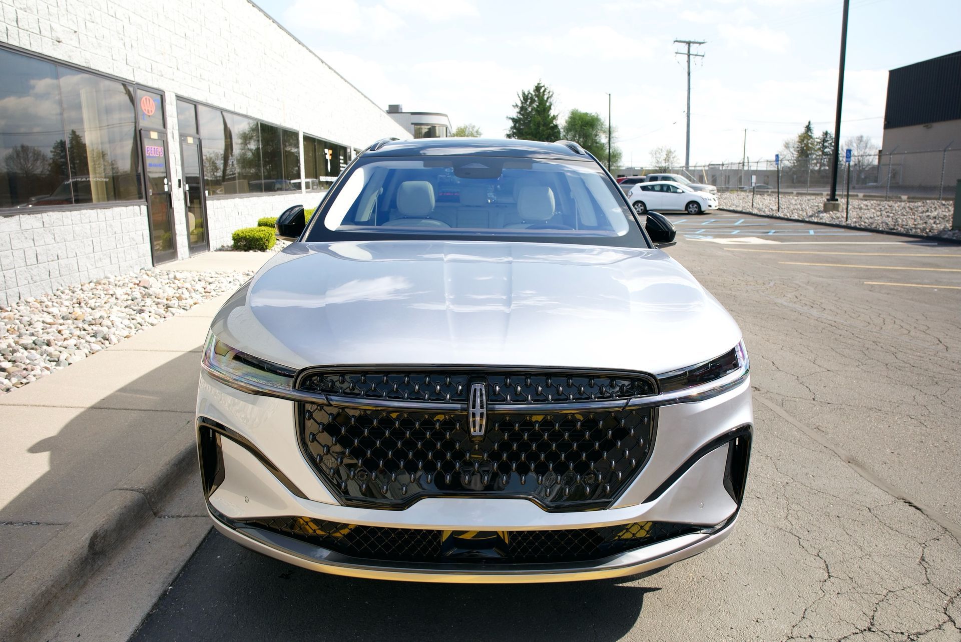 Silver SUV parked on a street beside a modern building, front view.