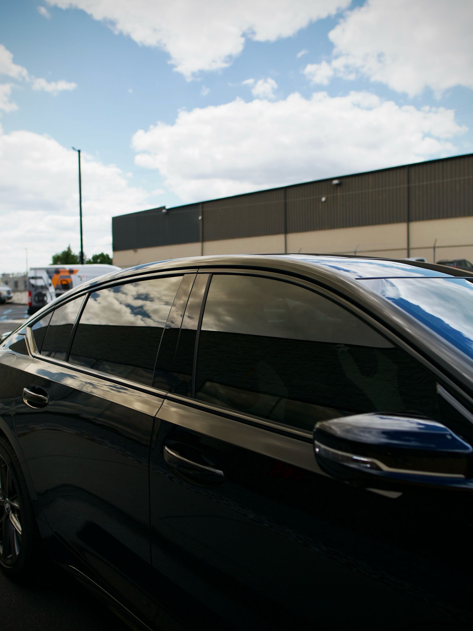 Black sedan with tinted windows parked outdoors under a cloudy sky