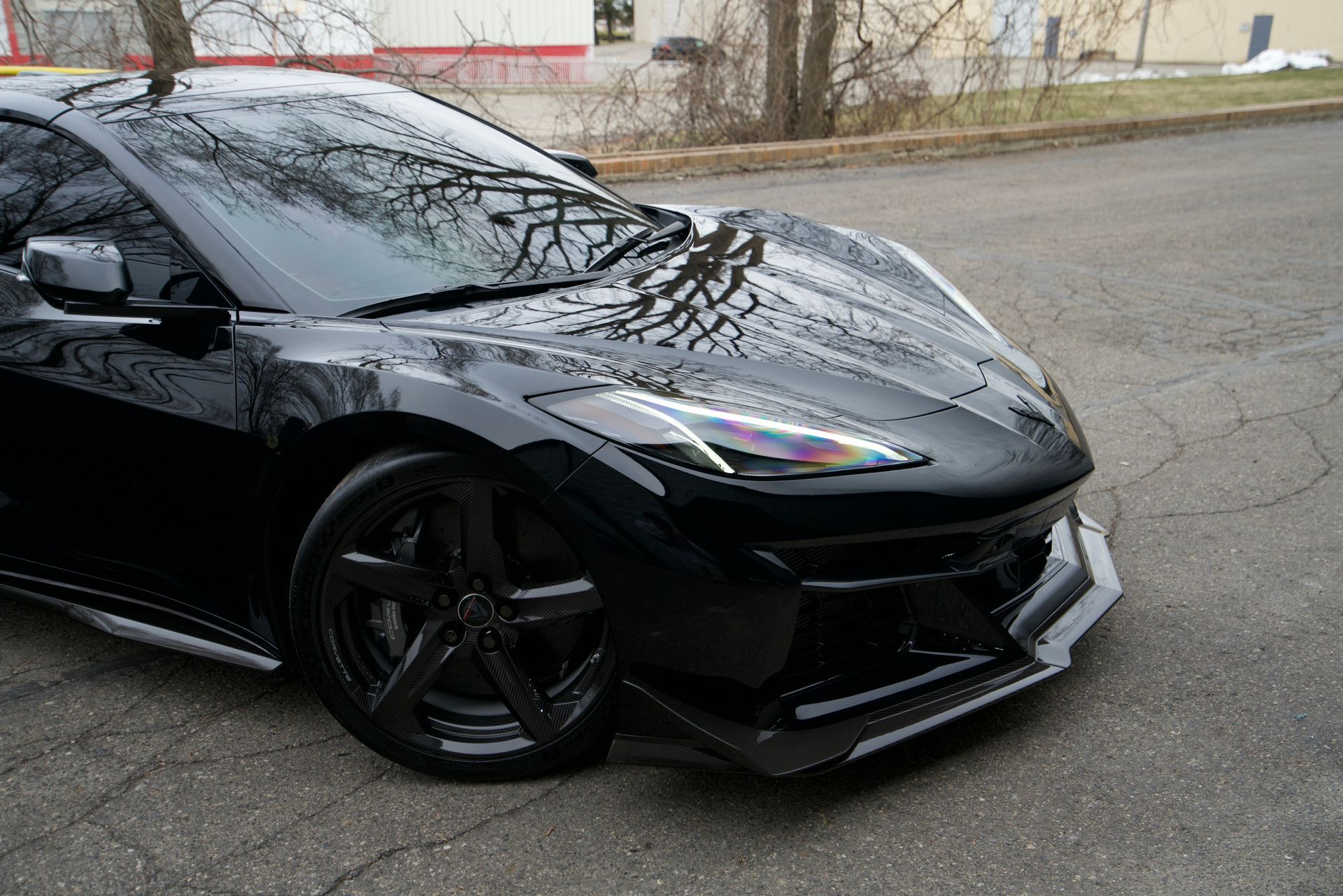 Black sports car parked on a wet street, front-left view, with tinted windows and a low body kit