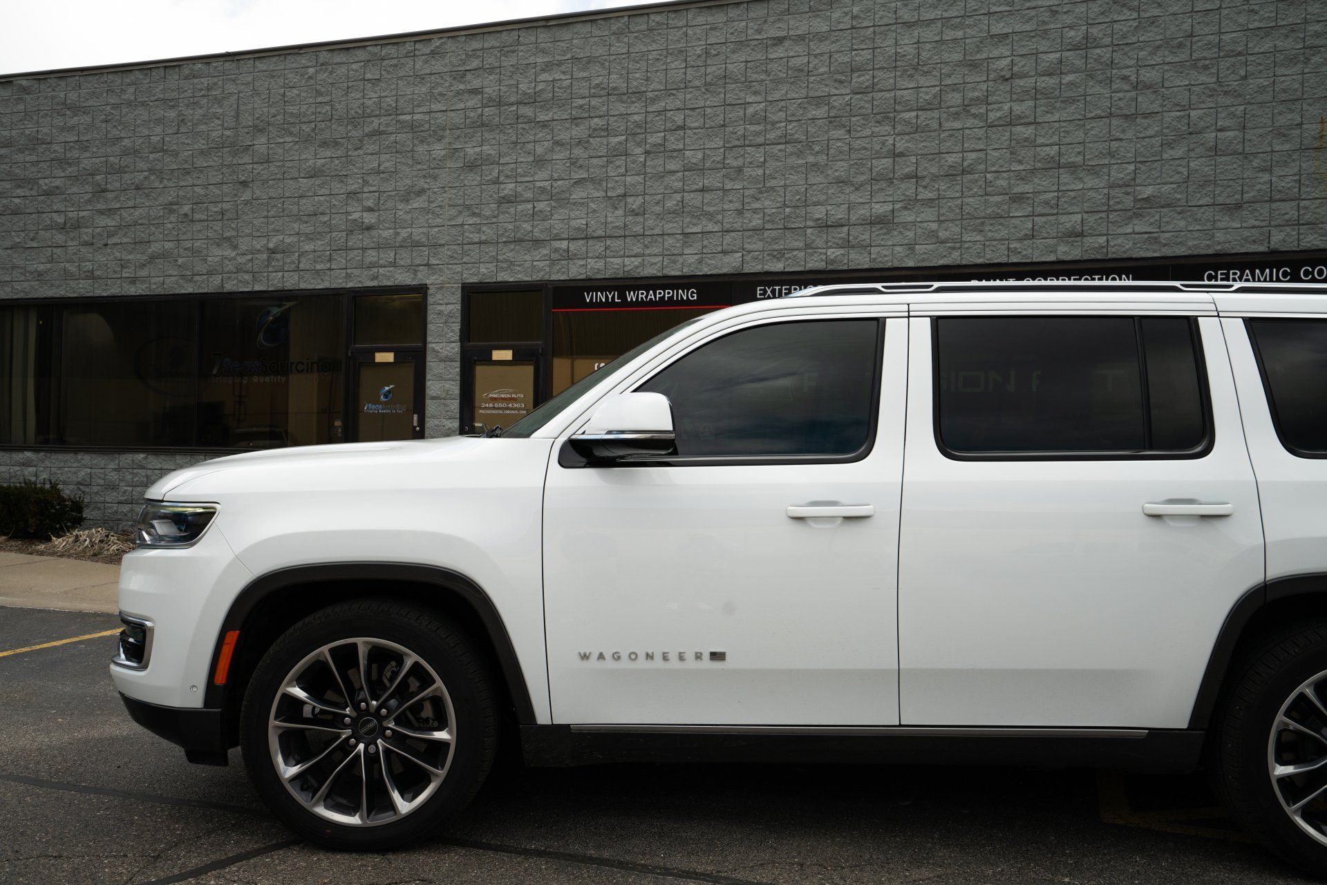 A white Grand Cherokee is parked in front of a brick building.
