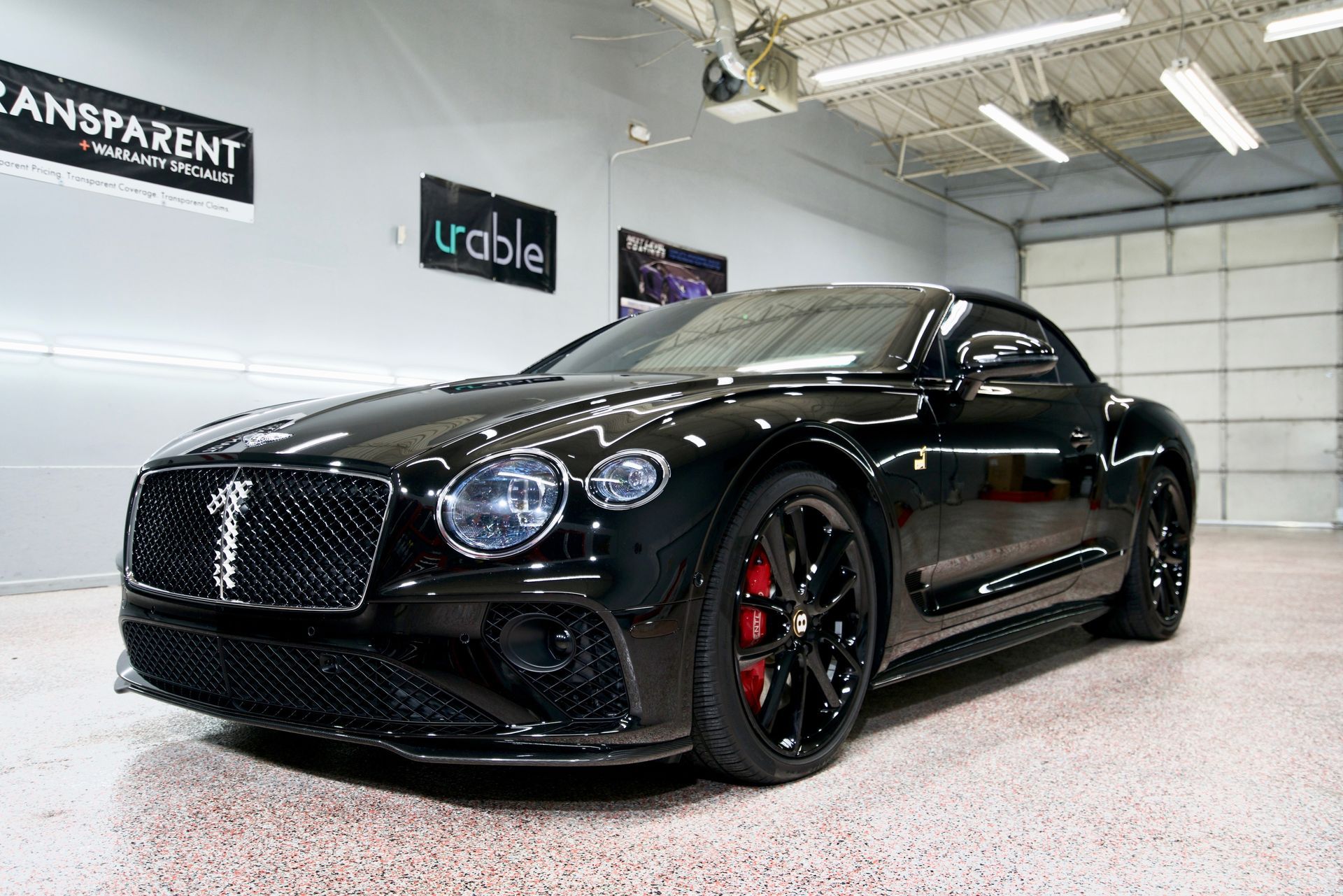 Black luxury sports coupe in a bright indoor showroom, front three-quarter view