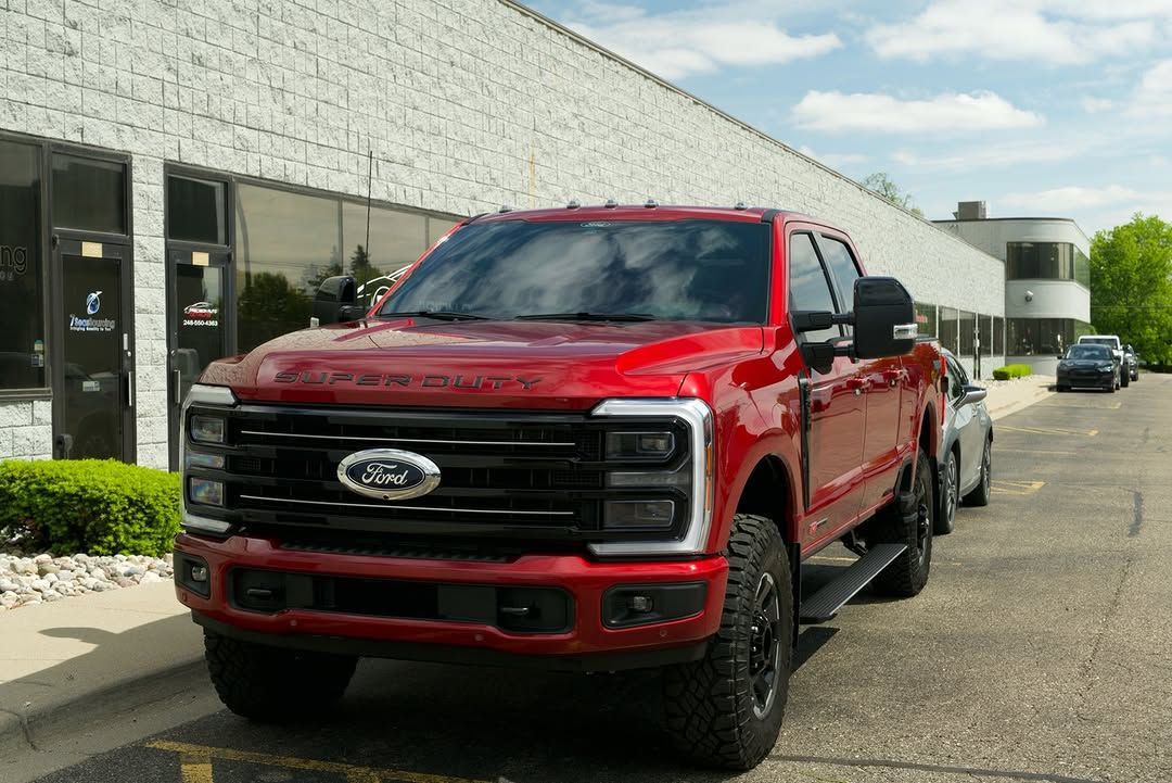 Red Ford pickup truck parked outside a commercial building on a sunny day