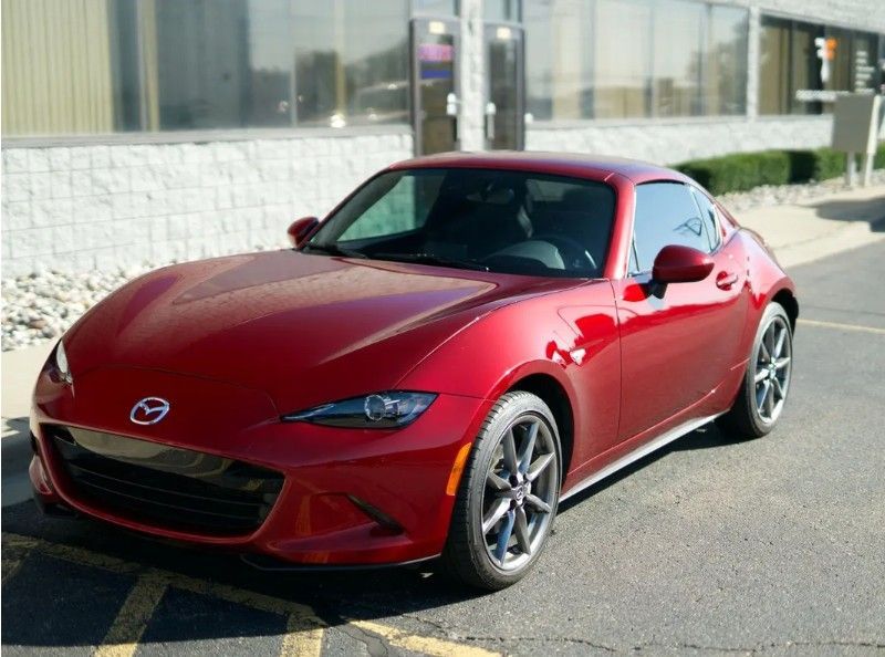 Red sports coupe parked outside a building in daylight.