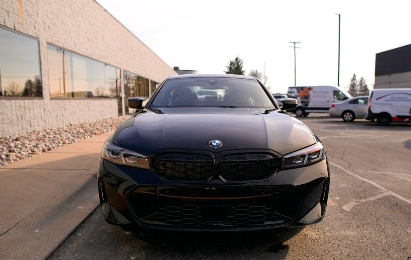 A black BMW sedan parked in a dealership lot during the day, viewed from the front.
