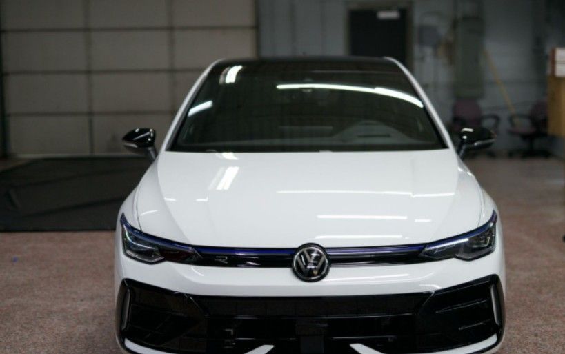 White Volkswagen Golf R, front view, black trim, blue accent, parked in a garage.