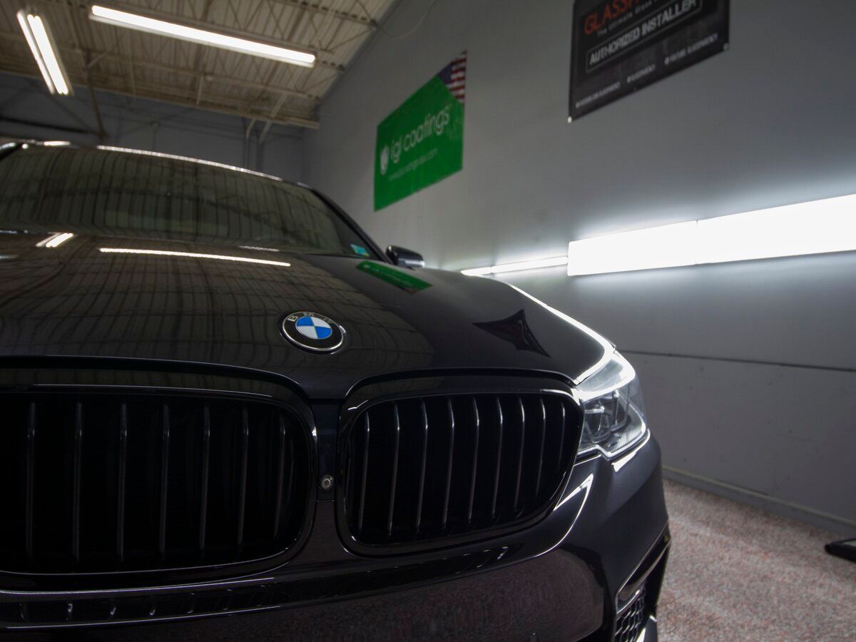 Black BMW car in a garage with bright lights; the BMW logo is visible on the hood.