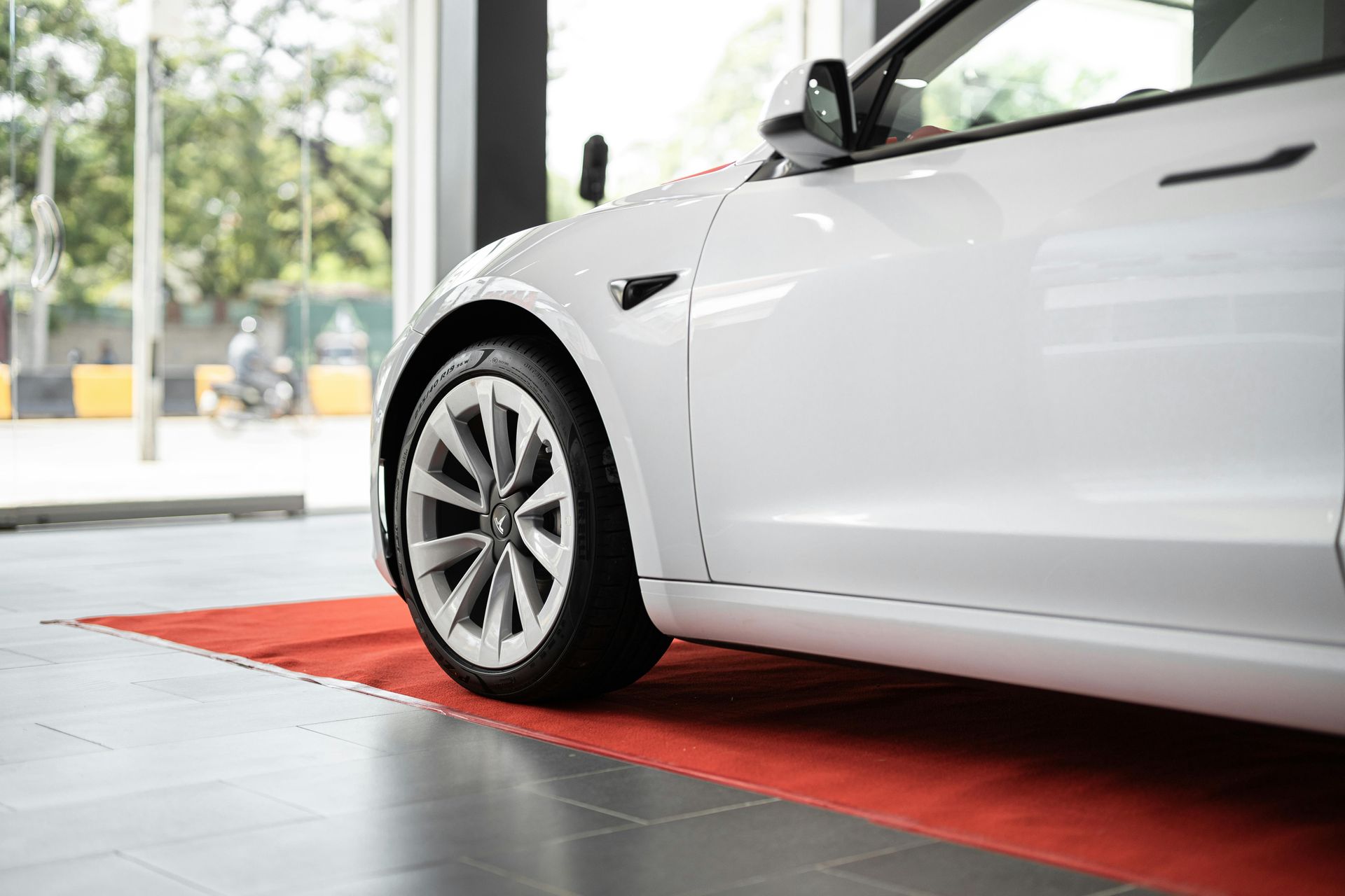 A white tesla model 3 is parked in a showroom.