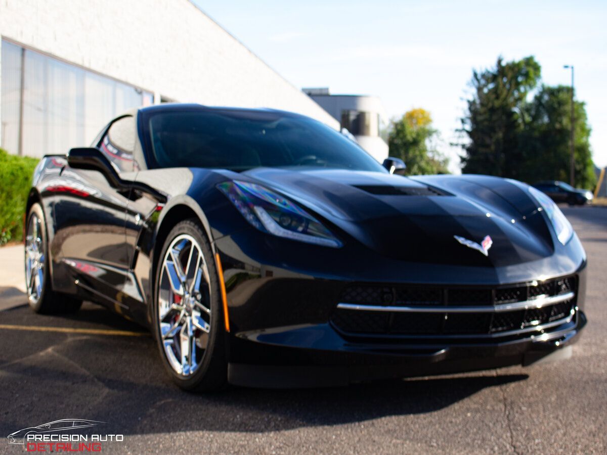 Black Chevrolet Corvette sports car parked on pavement.