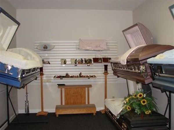 Interior of a funeral home displaying several open caskets in a neutral-toned room.