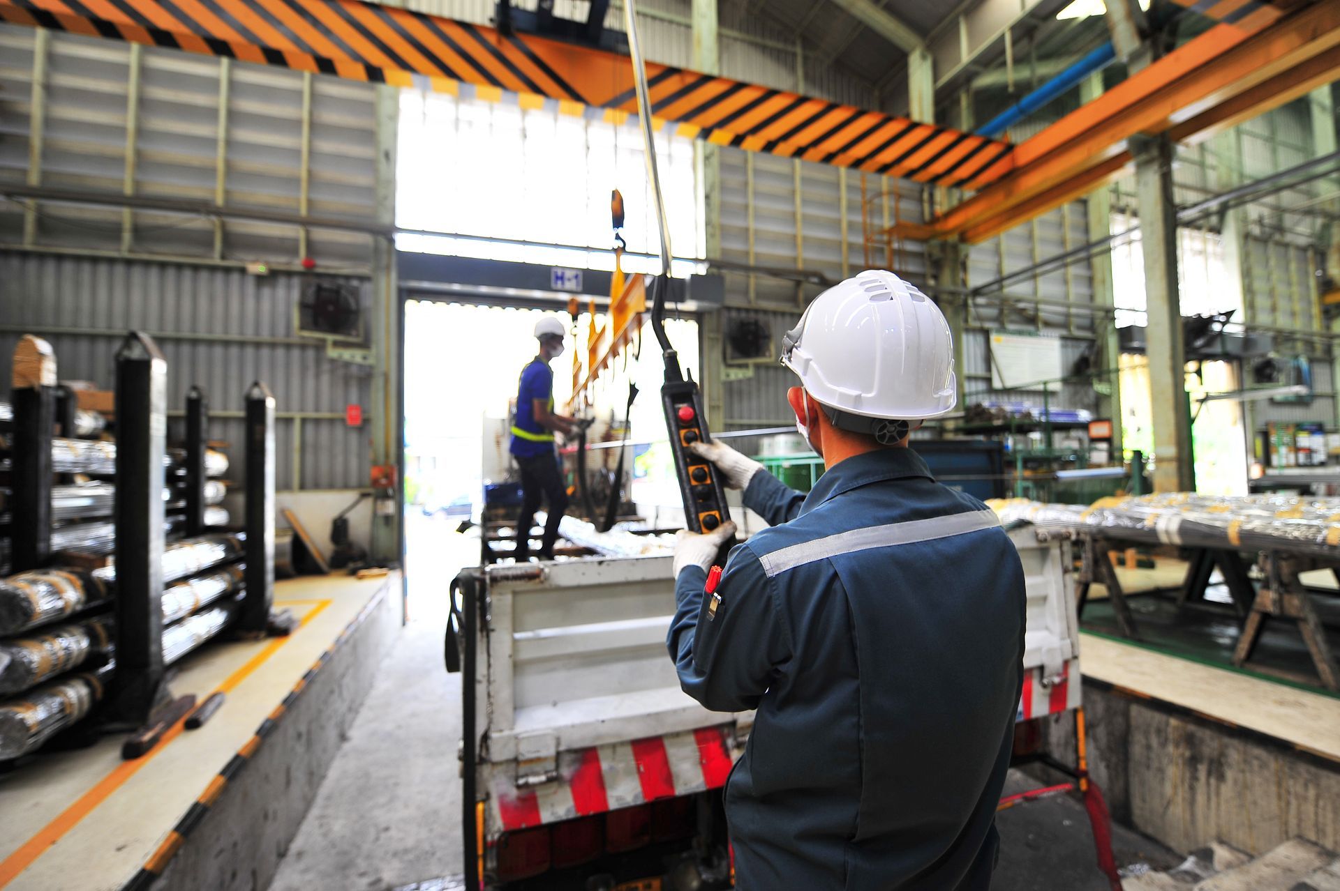 A worker in a hard hat operates an overhead crane.