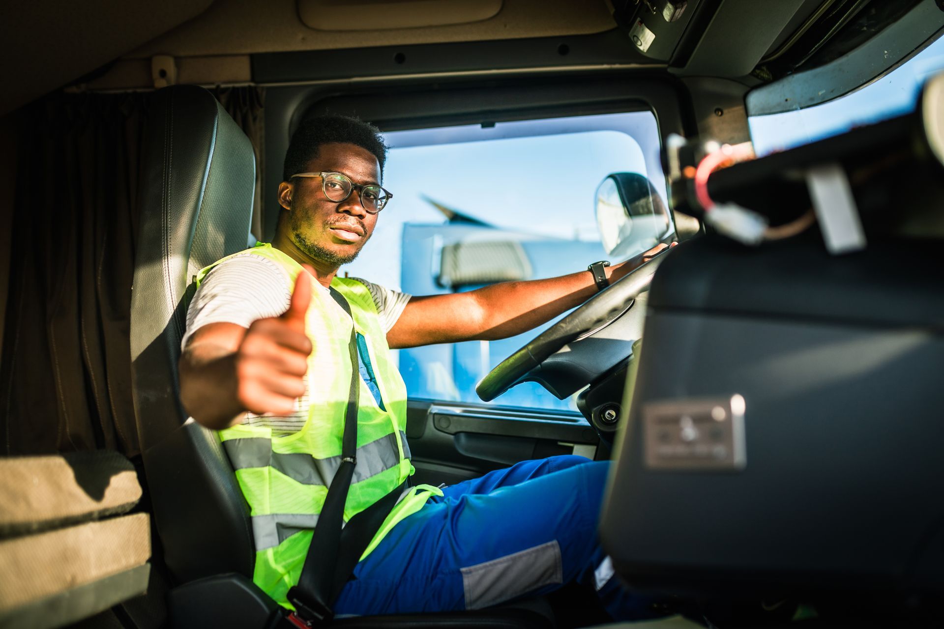 A truck driver wearing a high-visibility vest and glasses.