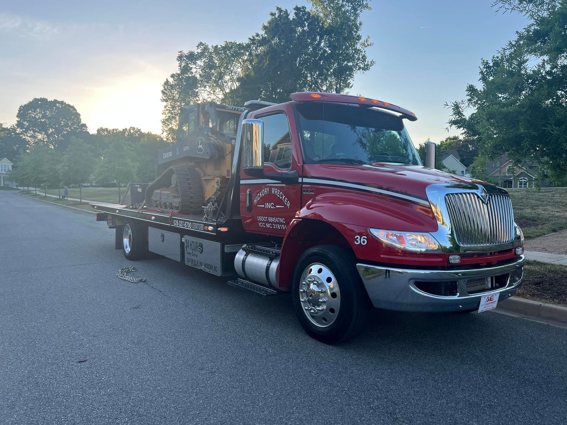 A red tow truck with a bulldozer on the back is parked on the side of the road.