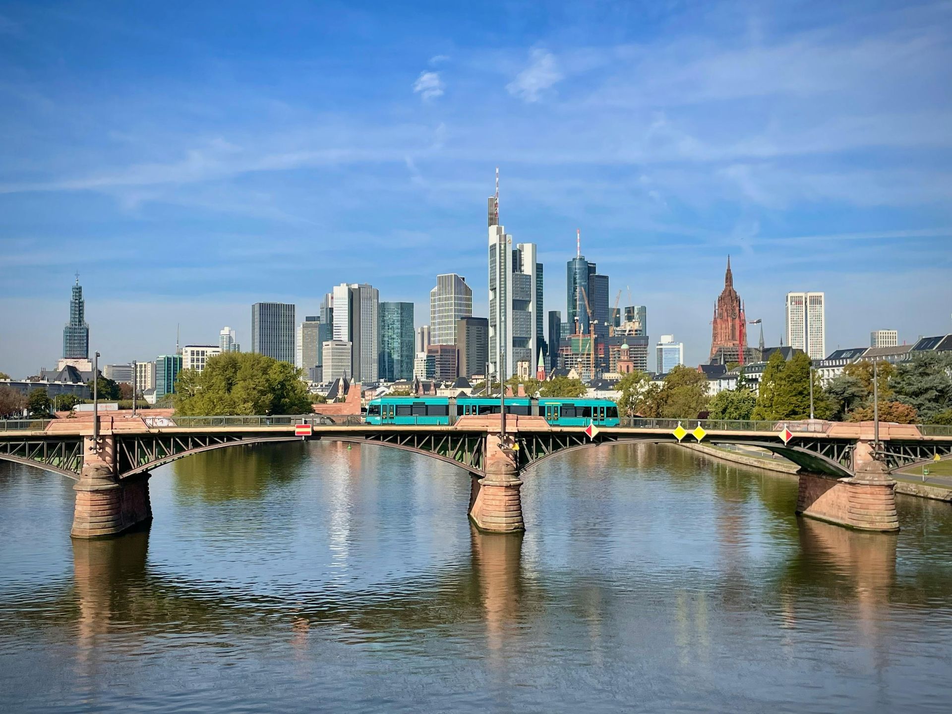 Stadtsilhouette mit einer Brücke über einen ruhigen Fluss unter blauem Himmel
