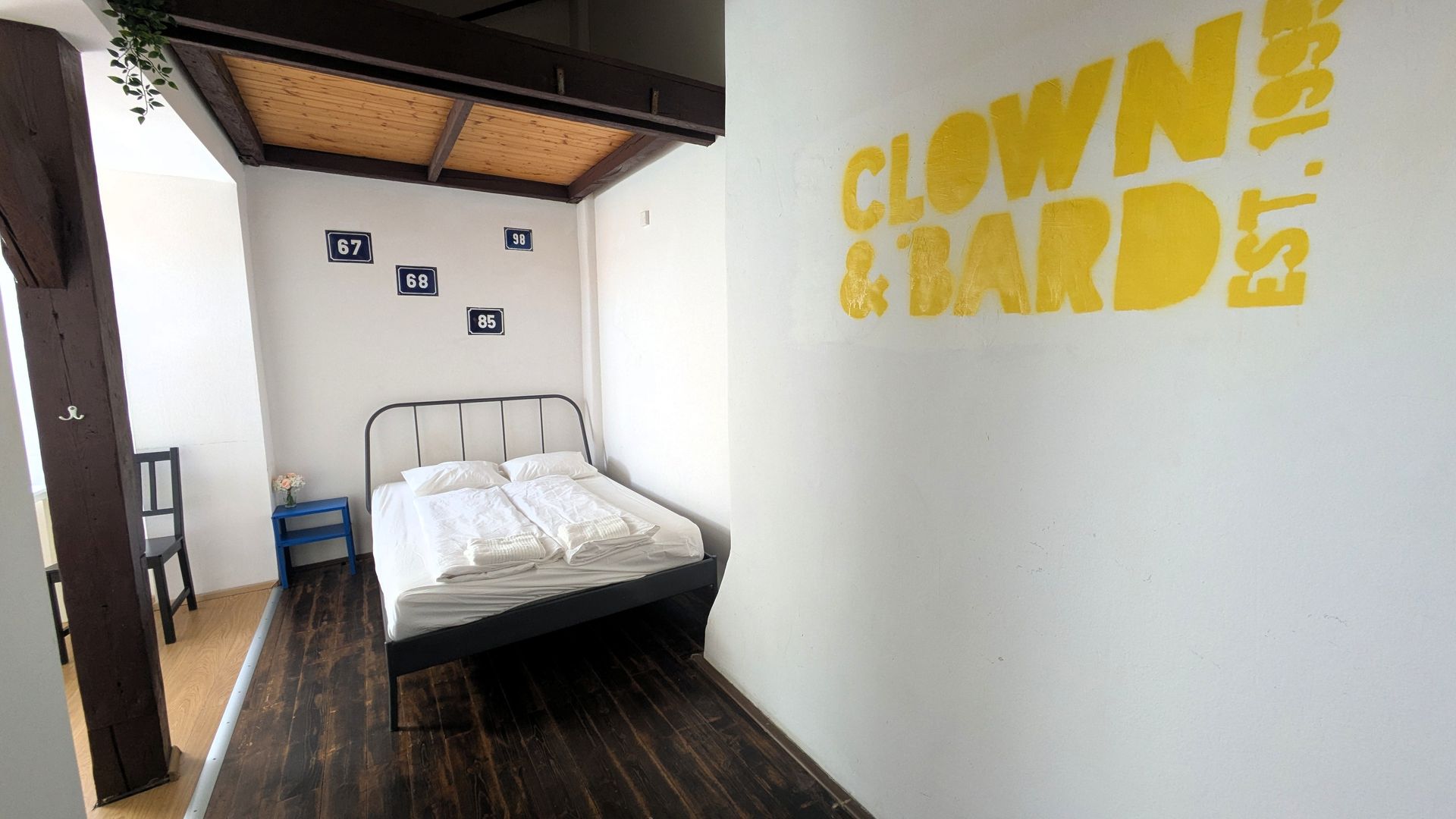 Small bedroom with bed, overhead platform, and wall with
