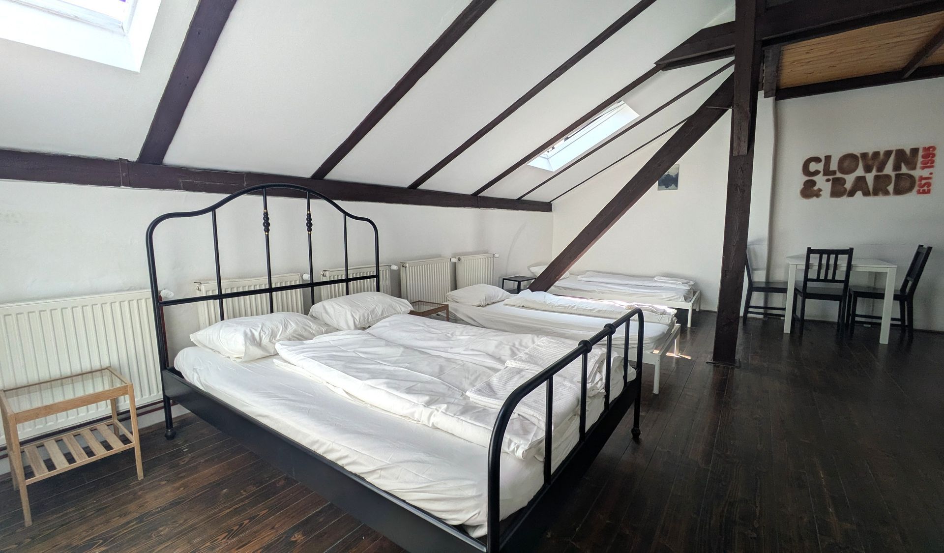 Attic bedroom with metal beds, white bedding, exposed beams, and a