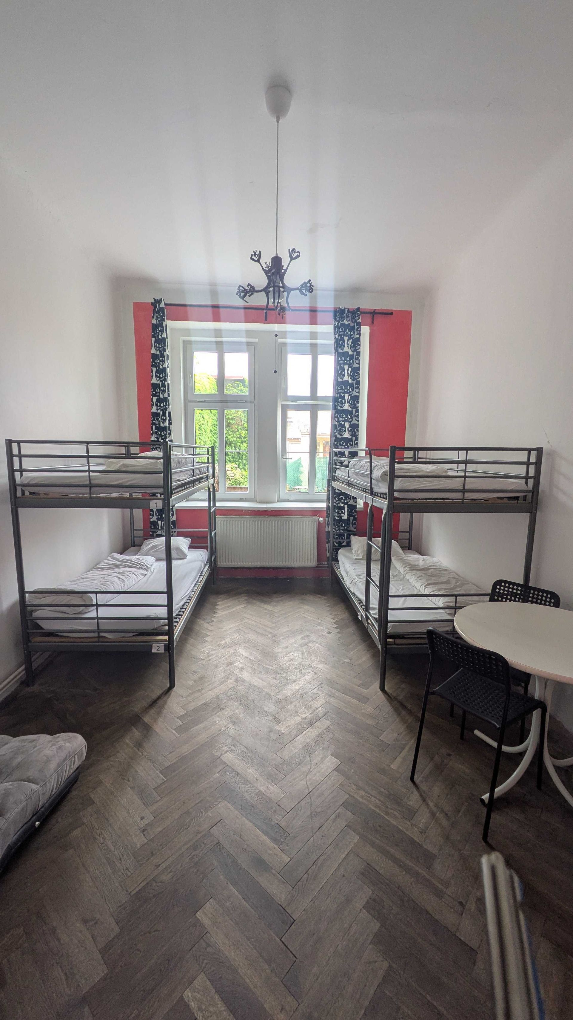 Bunk beds in a room with a window, table, and dark flooring.