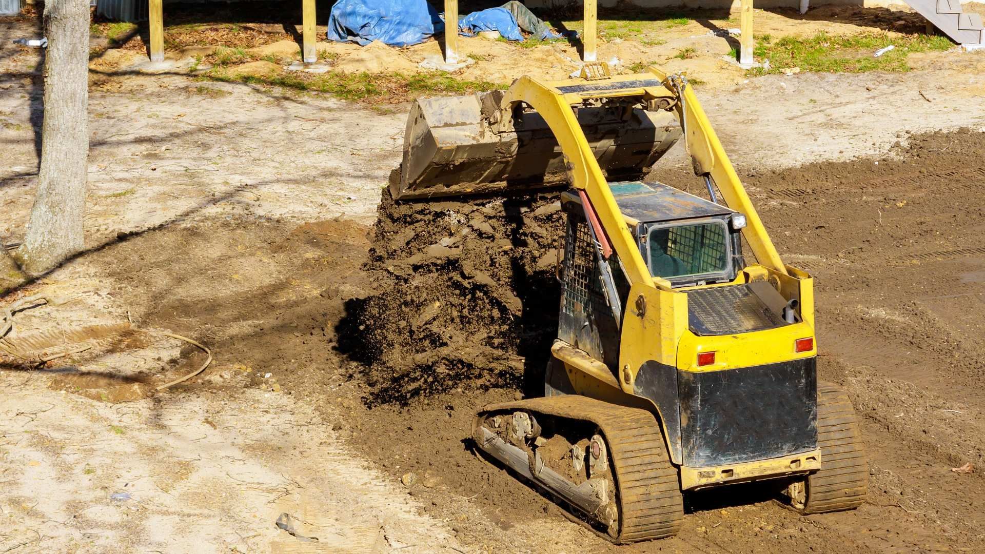 Yellow mini excavator digging soil at a construction site