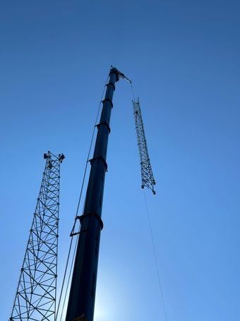 Red-and-white cellular tower with antennas against a clear blue sky