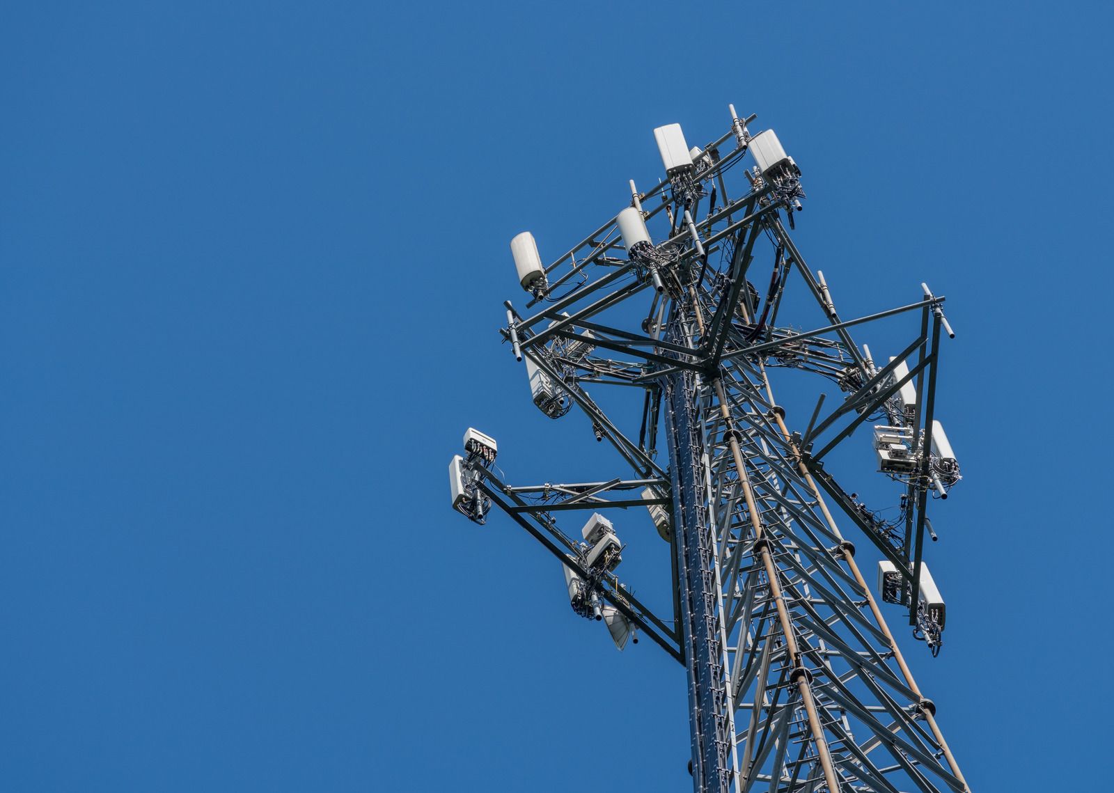 Construction site with excavator and bulldozer near a cell tower under a clear blue sky