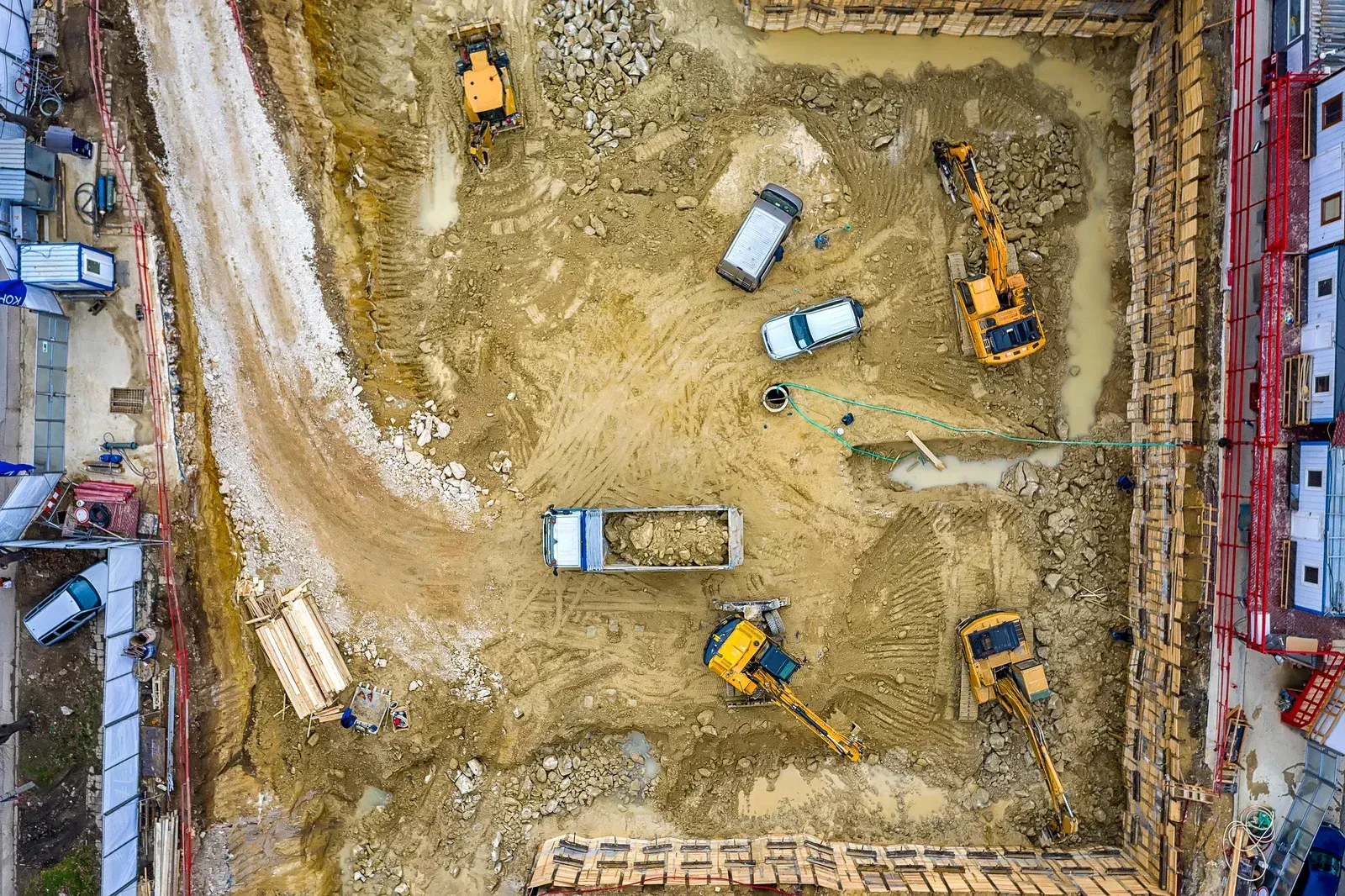 Aerial view of a construction site with excavators, trucks, and dirt roads inside a rectangular excavation
